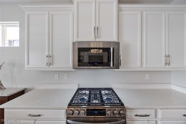 kitchen featuring light stone countertops, white cabinets, and stainless steel appliances