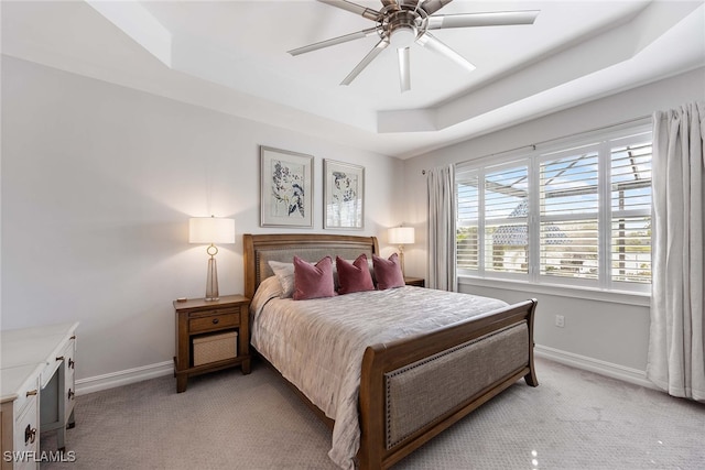 carpeted bedroom with a tray ceiling and ceiling fan