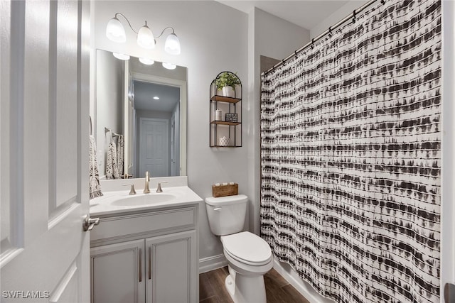 bathroom with wood-type flooring, vanity, toilet, and curtained shower