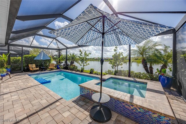 view of pool with an in ground hot tub, a patio, a water view, and glass enclosure