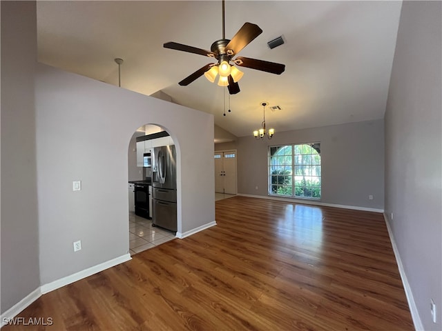 unfurnished living room with ceiling fan with notable chandelier, light hardwood / wood-style floors, and vaulted ceiling