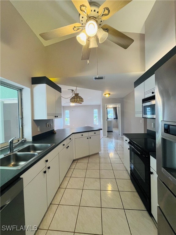 kitchen featuring white cabinets, stainless steel appliances, light tile patterned floors, and plenty of natural light