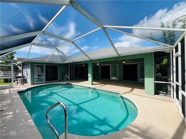 view of swimming pool with glass enclosure, a patio area, and ceiling fan