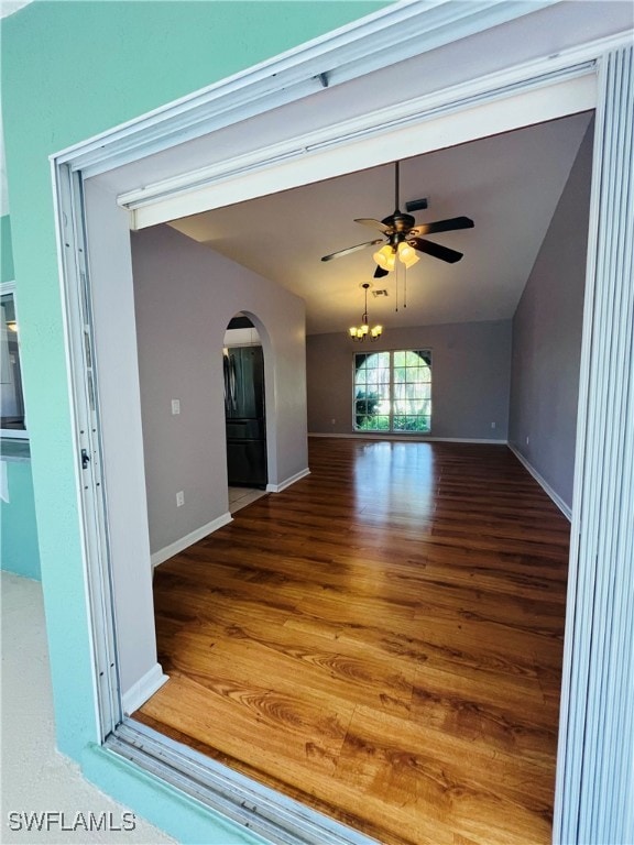 unfurnished living room featuring wood-type flooring and ceiling fan with notable chandelier