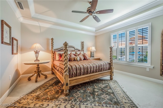 carpeted bedroom with a tray ceiling, ceiling fan, and ornamental molding