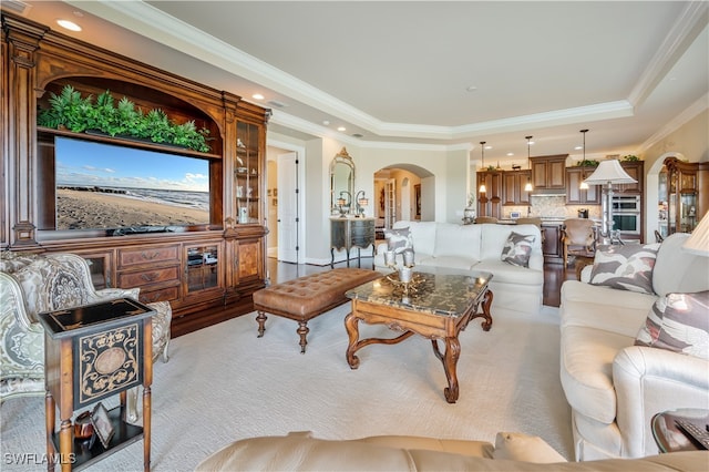 living room with light hardwood / wood-style floors, a raised ceiling, and crown molding