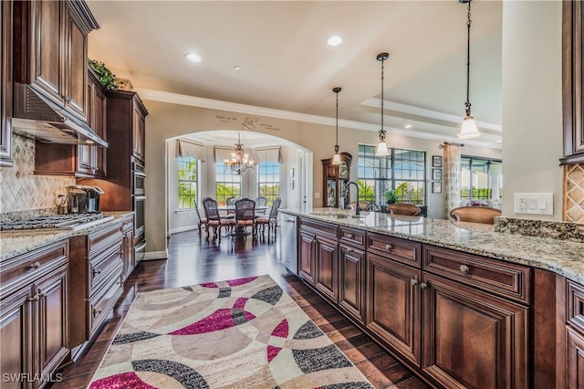 kitchen with tasteful backsplash, light stone counters, dark hardwood / wood-style flooring, pendant lighting, and appliances with stainless steel finishes