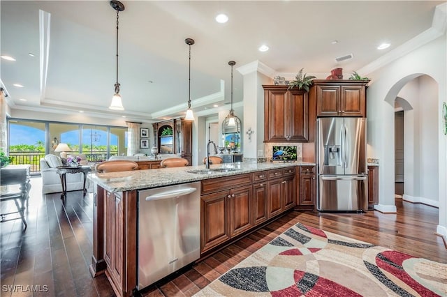 2555 Marquesa Royale Ln Unit 1-301, Naples, FL 34109 - kitchen featuring appliances with stainless steel finishes, crown molding, dark wood-style floors, arched walkways, and light stone countertops