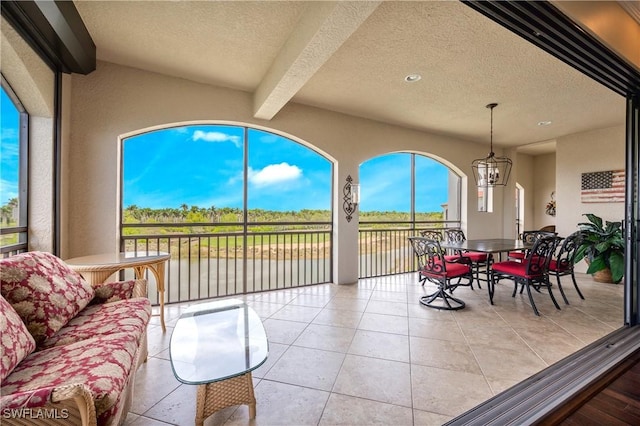 2555 Marquesa Royale Ln Unit 1-301, Naples, FL 34109 - sunroom with a textured ceiling, a water view, tile patterned flooring, beamed ceiling, and a chandelier