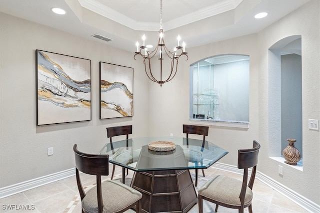 dining area with a raised ceiling, crown molding, and a notable chandelier