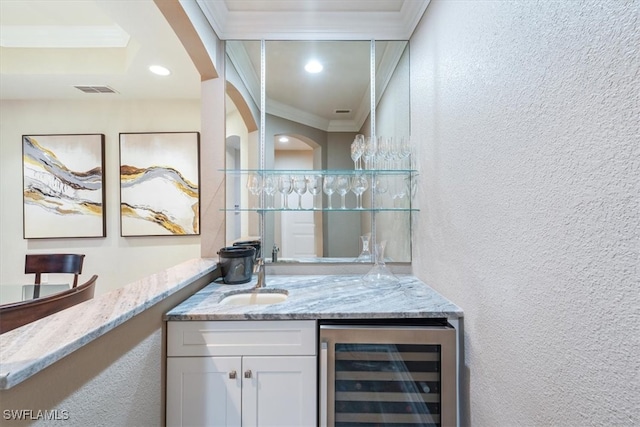 bar featuring light stone countertops, ornamental molding, beverage cooler, sink, and white cabinetry