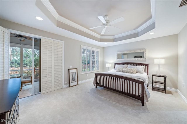 carpeted bedroom with access to exterior, multiple windows, a tray ceiling, and ceiling fan