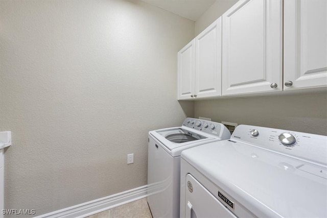 laundry area featuring cabinets, washing machine and dryer, and light tile patterned floors