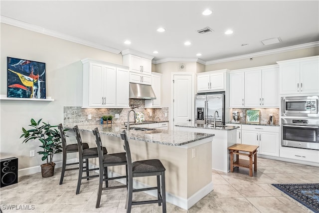 kitchen featuring stone counters, a kitchen breakfast bar, backsplash, white cabinetry, and appliances with stainless steel finishes