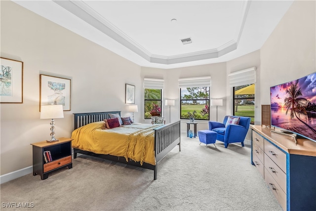 carpeted bedroom with a tray ceiling and ornamental molding