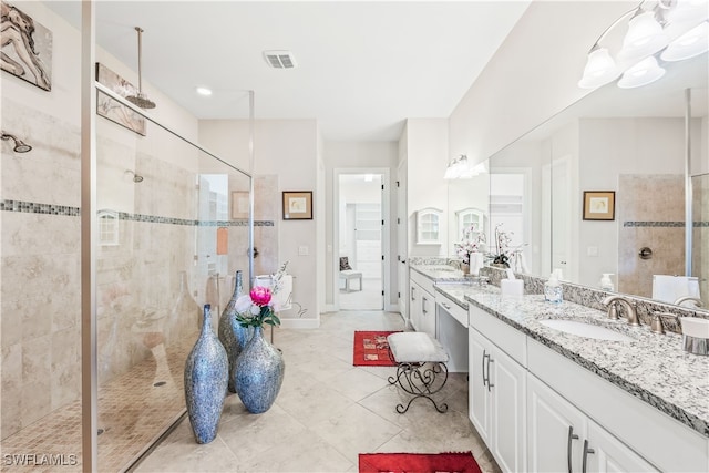 bathroom with tile patterned flooring, tiled shower, and vanity