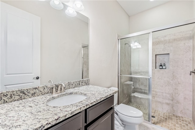 bathroom featuring a shower with door, vanity, and toilet