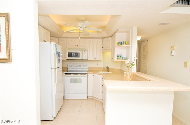 kitchen featuring kitchen peninsula, white appliances, sink, a tray ceiling, and ceiling fan