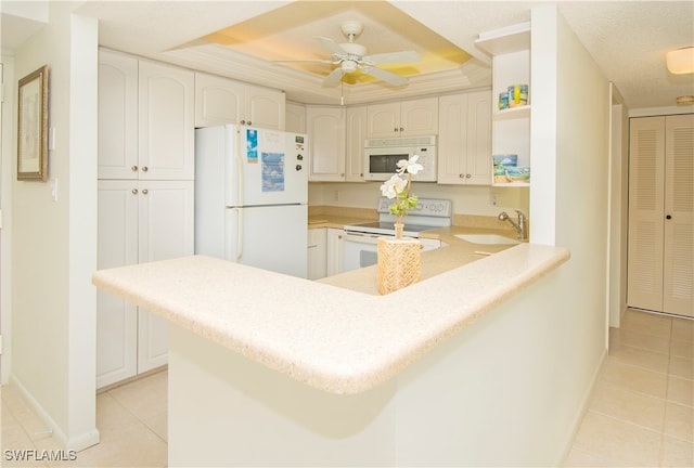 kitchen featuring white cabinets, kitchen peninsula, sink, a raised ceiling, and white appliances