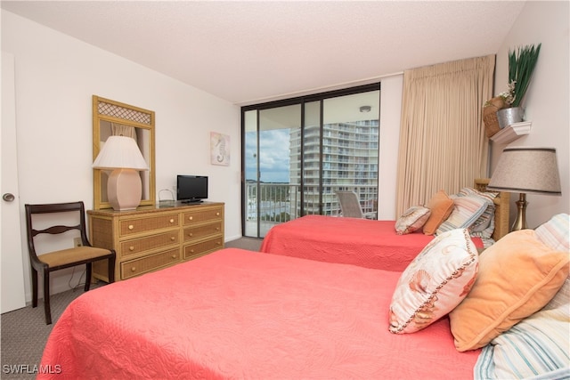 bedroom with a textured ceiling, carpet floors, and access to outside