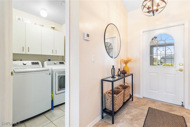 washroom featuring washer and clothes dryer, a notable chandelier, cabinets, and light tile patterned floors