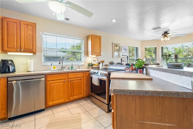 kitchen with a wealth of natural light, light tile patterned flooring, sink, and appliances with stainless steel finishes