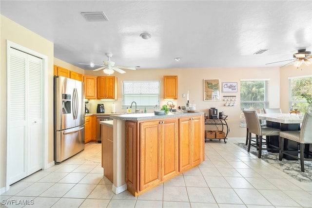 kitchen with ceiling fan, a center island, sink, stainless steel appliances, and light tile patterned floors