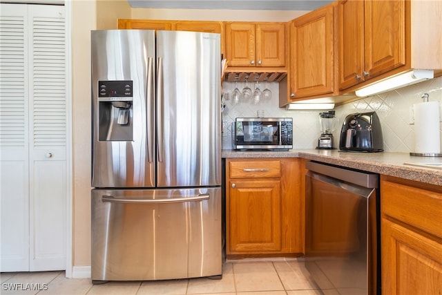 kitchen with light tile patterned floors, appliances with stainless steel finishes, and tasteful backsplash