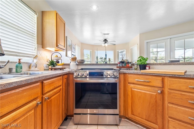 kitchen featuring ceiling fan, stainless steel range, light tile patterned flooring, and a healthy amount of sunlight