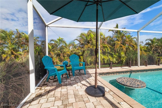 view of pool featuring glass enclosure and a patio