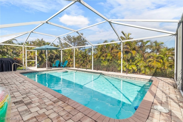 view of swimming pool with glass enclosure and a patio area