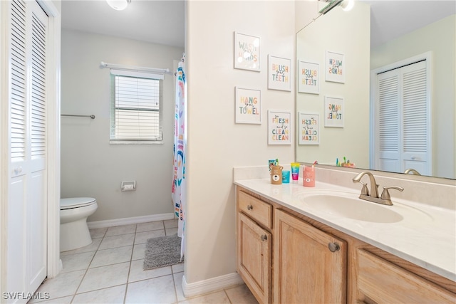 bathroom with toilet, vanity, and tile patterned floors