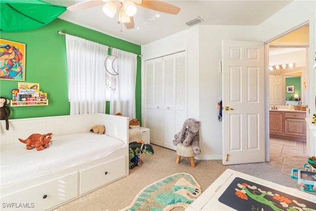 bedroom with a closet, light colored carpet, ceiling fan, and sink