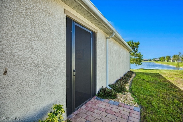 view of exterior entry featuring a yard and a water view