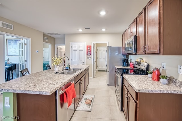 kitchen with a center island with sink, appliances with stainless steel finishes, sink, and light tile patterned flooring