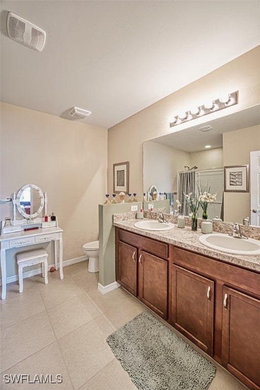 bathroom with toilet, vanity, and tile patterned floors