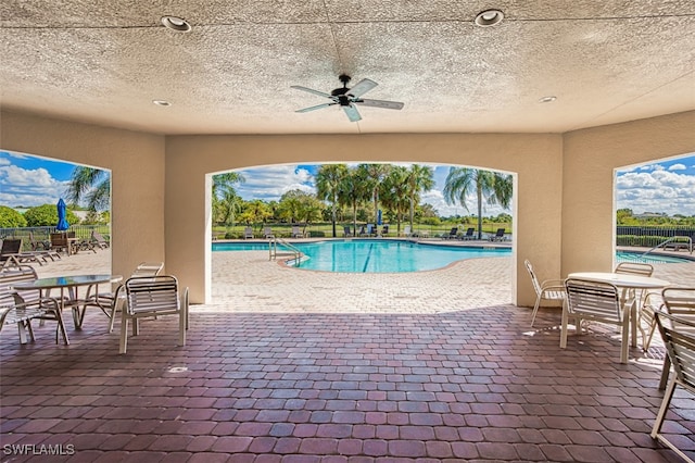 view of swimming pool with ceiling fan and a patio area