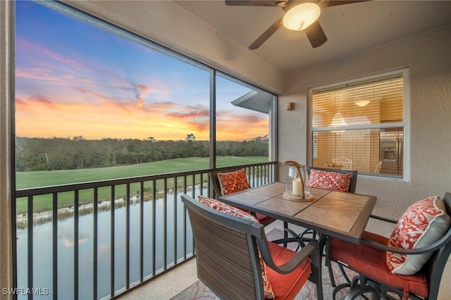 sunroom with a water view and ceiling fan