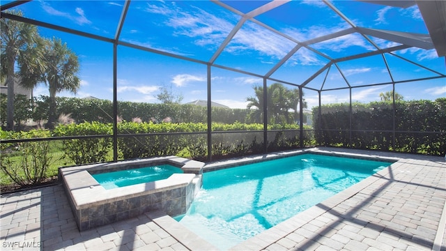 view of pool featuring glass enclosure, an in ground hot tub, and a patio