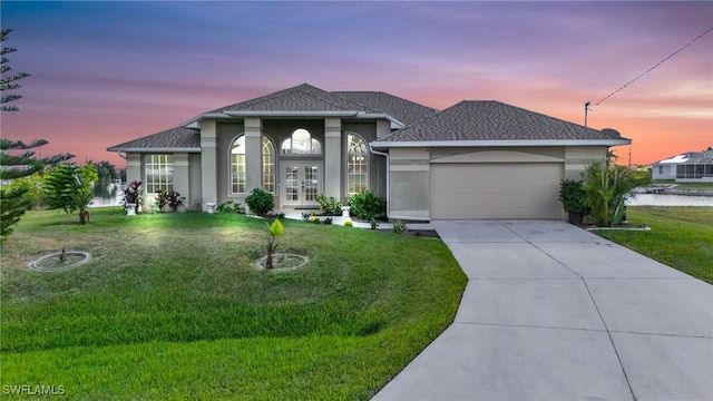 view of front of property with french doors, a water view, a garage, and a yard