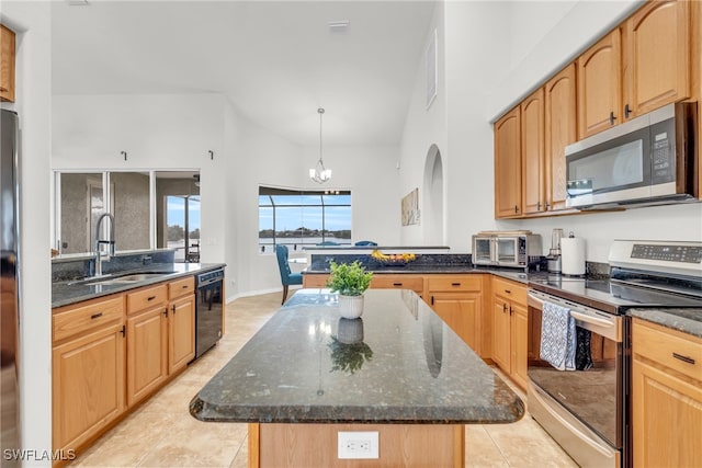 kitchen with a kitchen island, appliances with stainless steel finishes, decorative light fixtures, sink, and dark stone counters