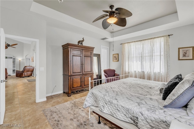 bedroom featuring light tile patterned floors, ceiling fan, and a tray ceiling