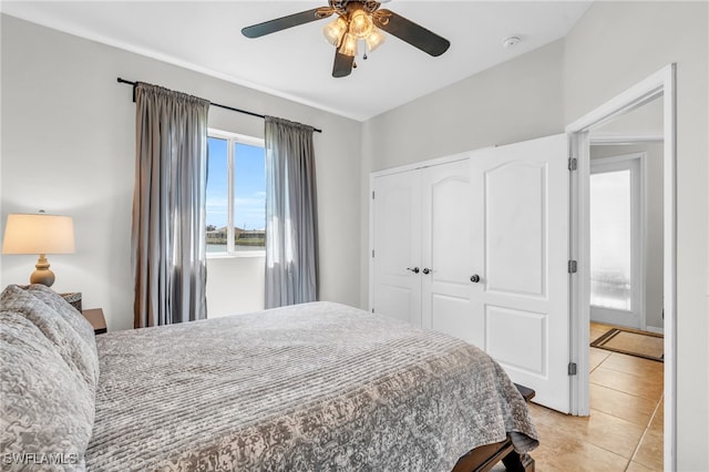 bedroom with light tile patterned flooring, ceiling fan, and a closet