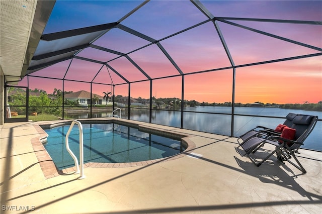 pool at dusk with a water view, a patio, and a lanai