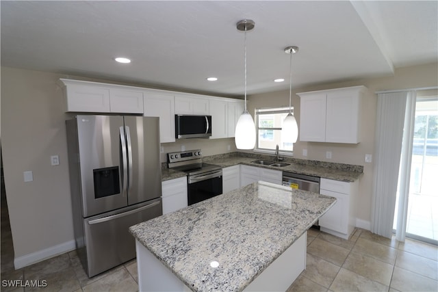 kitchen with stainless steel appliances, hanging light fixtures, sink, white cabinets, and a center island