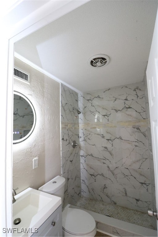 bathroom featuring vanity, toilet, and tiled shower