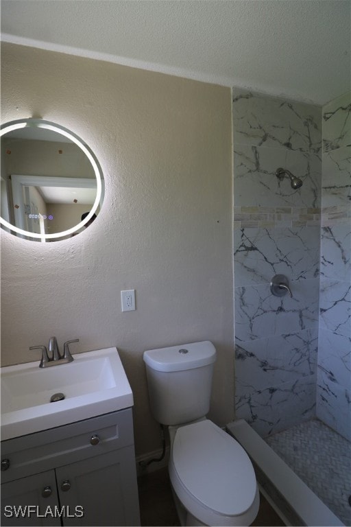 bathroom with toilet, vanity, and a tile shower