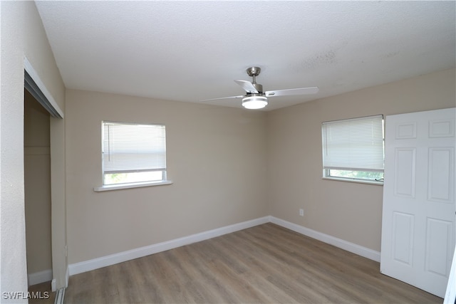 unfurnished bedroom with a closet, hardwood / wood-style floors, ceiling fan, and a textured ceiling