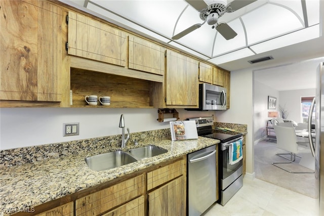 kitchen with stainless steel appliances, sink, ceiling fan, and light stone countertops