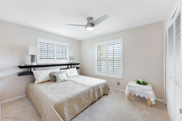 bedroom with light colored carpet, ceiling fan, and a closet